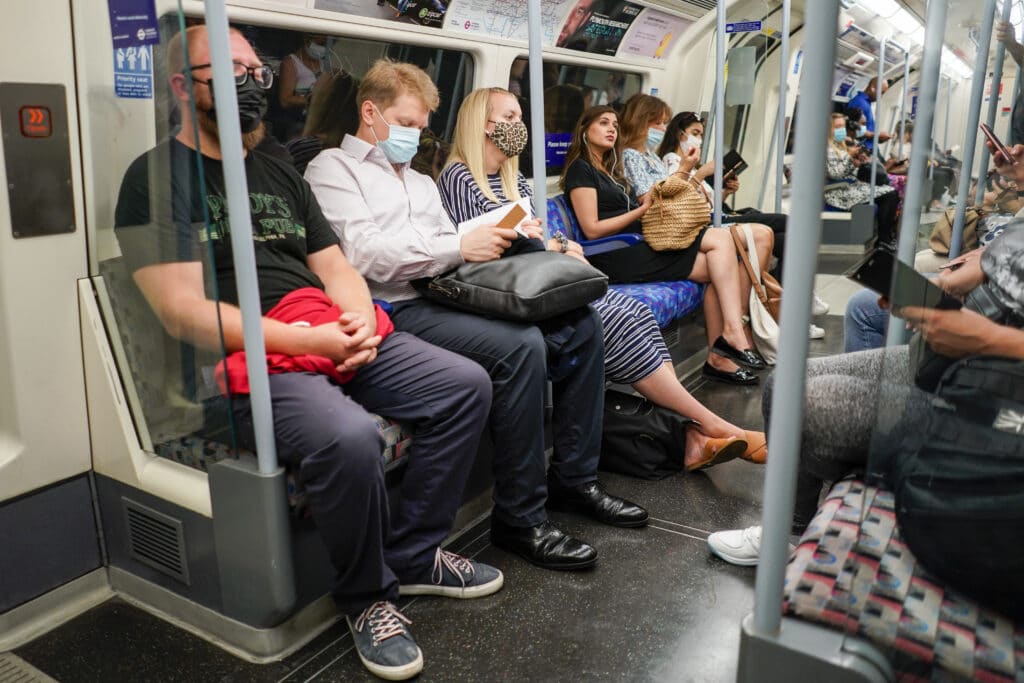 people sit on an Underground train in London, as face masks and social distancing rules are relaxed
