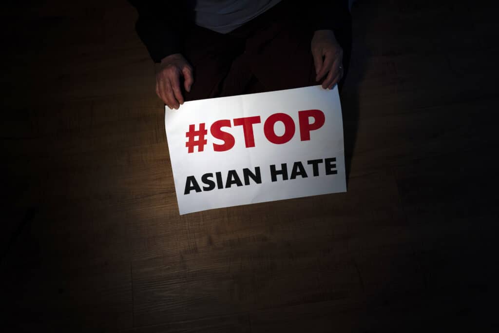 Jen Ho Lee, a 76-year-old South Korean immigrant, poses in her apartment in Los Angeles with a sign from a recent rally